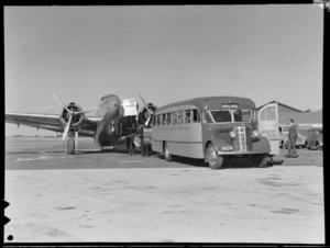 Freight being unloaded from a New Zealand National Airways Corporation Lockheed Lodestar aeroplane, onto a Johnstons Airways Transport bus, Mangere, Auckland