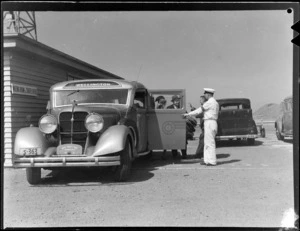 Passengers embarking an Airways Service bus, parked outside a building with signage reading:'Waiting Room and Traffic Office', Rongotai Airport, Wellington
