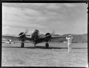 An unidentified member of New Zealand National Airways Corporation ground crew sigalling pilot of Lockheed Lodestar Electra aeroplane, Rongotai Airport, Wellington