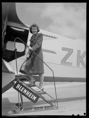 An unidentified female passenger emplaning a New Zealand National Airways Corporation Dragon Rapide aeroplane, 'Tikaka', at Rongotai airport, Wellington, before departure to Blenheim