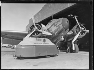 Lockheed Lodestar aeroplane 'Karoro' ZK-AHU, being refueled by an unidentified engineer, from Shell Oil Company type 6 refueling trailer, outside Union Airways of New Zealand Ltd hangar, Mangere, Auckland