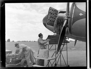 New Zealand National Airways Corporation ground crew and an unidentified passenger loading luggage onto an aeroplane, location unidentified