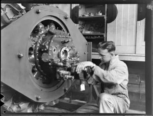 An unidentified aircraft engineer assembling an engine in New Zealand National Airways Corporation workshop, Milson, Palmerston North