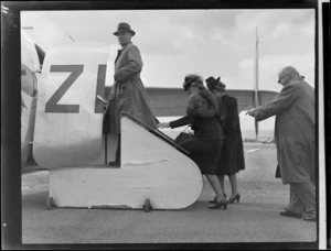 Group of unidentified passengers, including women wearing furs, boarding a New Zealand National Airways Corporation aeroplane at Palmerston North Airport