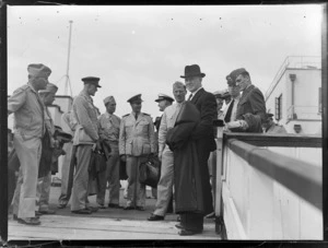 Portrait of Hon F Jones, NZ Minister of Defence with unidentified military personnel, on a gangway preparing to leave for the US on a PAA flying boat, Mechanic's Bay Auckland