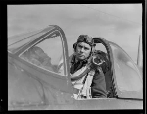 Portrait of Squadron Leader D Greig in flight gear within the cock pit of his plane, Ardmore Aerodrome, Auckland Region