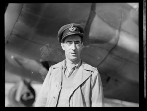 Portrait of Flying Officer G Marcean DFC of 40th Squadron in front of a [Dakota?] cargo aeroplane, Whenuapai Airfield, Auckland