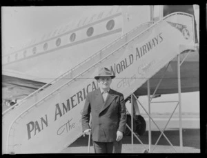 A portrait of Mr Walter Miller standing in front of PAWA (Pan American World Airways) passenger gangway, Whenuapai Airbase, Auckland