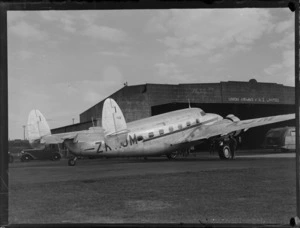 New Zealand National Airways Corporation (NZNAC) Lockheed Lodestar aircraft, 'Kotare' (ZK-AJM) at Mangere Aerodrome, Auckland, showing 'Kotare' sitting in front of the Union Airways of New Zealand Ltd hangar