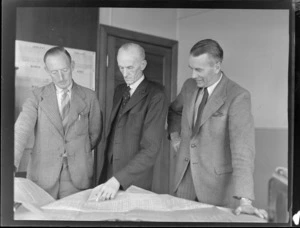 Mr George Bolt (centre), Chief Engineer, Tasman Empire Airways, Mr G Wells (left) and Mr E Nicholls (right), discussing plans of New Aircraft, with his assistant engineer and radio overseer