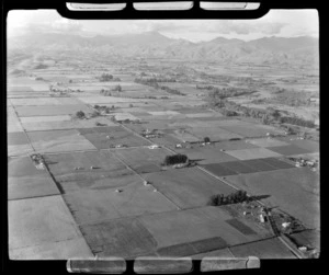 View of pastoral fields and a few houses with a river and mountains beyond, Nelson Region