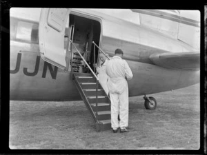 View of unidentified plane crew adjusting gangway on visiting British Vickers Viking passenger plane G-AJJN, location unknown