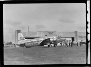 Visiting British Vickers Viking passenger plane G-AJJN in front of Union Airways plane hangar with unidentified men, Milson Aerodrome, Palmerston North, Manawatu-Whanganui Region