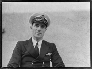 Portrait of TEA (Trans Empire Airways) Captain Jack Burgess in uniform, in front of an unknown building, [Auckland City?]
