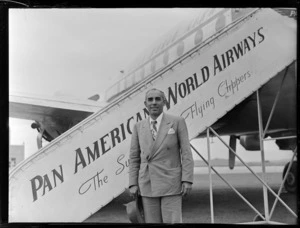 Portrait of Mr Peter Isaza in front of a Clipper Class Pan American World Airways aeroplane and gangway, Whenuapai Airfield, Auckland