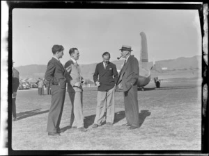 View of (L to R) unidentified Co-pilot and a Naval man, (Pilot) P Roberts and Mr Dickson (Director) in front of visiting British Vickers Viking passenger plane G-AJJN, location unknown