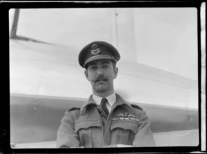 Portrait of Squadron Leader R M Trousdale in RNZAF uniform in front of the visiting British Vickers Viking passenger plane G-AJJN, [Paraparaumu Airfield, Wellington Region?]