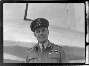 Portrait of Wing Commander Baird in RNZAF uniform in front of visiting British Vickers Viking passenger plane G-AJJN, location unknown