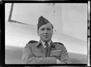 Portrait of Squadron Leader Baigent in RNZAF uniform in front of visiting British Vickers Viking passenger plane G-AJJN, location unknown