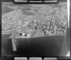 Wellington City southern wharf area with docked ships (now the Overseas Terminal) and State Coal factory, with the suburbs of Mt Victoria and Te Aro with the Dominion Museum on Buckle Street beyond