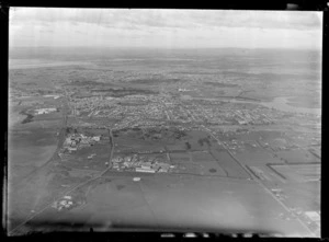 Passenger Transport Company coverage over the suburb of Otahuhu with farmland, a timber factory and the Great South Road in the foreground, looking to East Tamaki, Auckland City