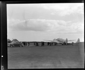 View of unidentified passengers disembarking from NZ NAC (National Airways Corporation) Lodestar 'Kotare' KZ-AJM passenger plane at Invercargill Airport, Southland Region