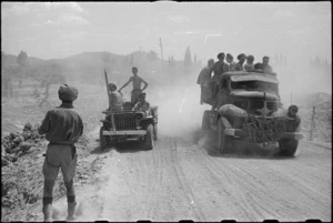 New Zealand Division personnel and vehicles loom up through the dust before Lignano, Italy, World War II - Photograph taken by George Kaye