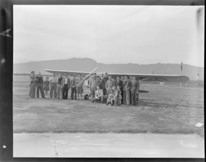 Group of unidentified people, including children, in front of an Auster ZK-AOB airplane, Westport airport