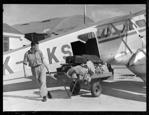 Unidentified staff member unloading luggage from a NAC (National Airways Corporation) Rapide [ZK-AKS?] airplane, Nelson