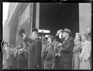 The Honourable F Jones and other unidentified people, waving to passengers on the inaugural British Commonwealth Pacific Airlines' trans Pacific flight to Vancouver, Whenuapai Airport, Auckland
