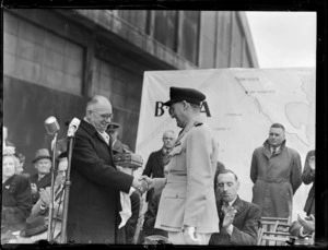 Captain P Taylor, right, with an unidentified man, on stage at opening ceremony for British Commonwealth Pacific Airlines' trans Pacific service, Whenuapai Airport, Auckland