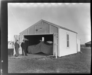 Aircraft hangar belonging to Mr A J McIntosh (right), with unidentified man next to doorway of hangar, at Invercargill Airport