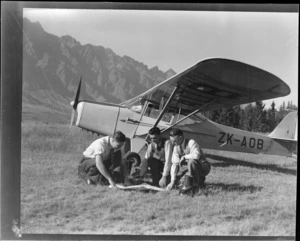 D [Greig?], at left, with Leo White and T Ewart, beside a Auster Autocrat aeroplane, ZK-AOB, at Queenstown
