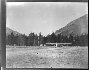 Auster Autocrat monoplane, ZK-AOB, grounded in a field, with two unidentified children standing nearby, Queenstown, Otago Region