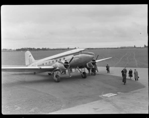 Aircraft 'Dakota', including passengers leaving aircraft, at Harewood Aerodrome (Christchurch International Airport)