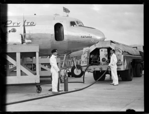 Two unidentified men refueling Douglas DC-4 Skymaster aeroplane 'Tatana' VH-AND, at Whenuapai Airport, Auckland