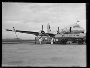 Three unidentified men refueling a Douglas DC-4 Skymaster 'Tatana' VH-AND, with an 'Intava' tanker, Whenuapai Airport, Auckland