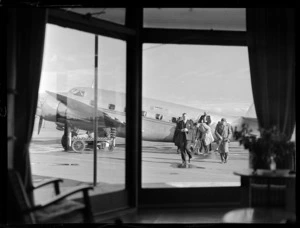 View of unidentified passengers disembarking NZ NAC ((National Airways Corporation) Lockheed 18-56 Lodestar aeroplane 'Kawatere' ZK-ANA at Harewood Airport, Christchurch City, Canterbury Region