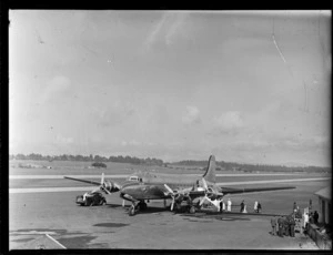 TAA (Trans Australian Airways) Skymaster DC4 passenger plane 'Thomas Mitchell' with unidentified disembarking passengers, ground crew and military personnel at Whenuapai Airport, Auckland City
