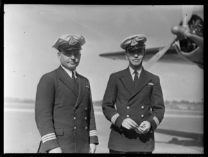 Portrait of (L to R) TAA (Trans Australian Airways) Senior Captain A Bayne and Captain L Morey in front of TAA Skymaster DC4 passenger plane 'Thomas Mitchell' at Whenuapai Airport, Auckland City