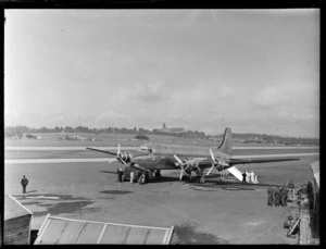 TAA (Trans Australian Airways) Skymaster DC4 passenger plane 'Thomas Mitchell' with unidentified ground crew and military personnel at Whenuapai Airport, Auckland City