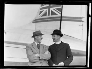 Portrait of (L to R) G L Steadman of Dunedin and Father W W Ainsworth a Catholic Priest, in front of visiting British Vickers Viking passenger plane G-AJJN at [Whenuapai Airport, Auckland City?]