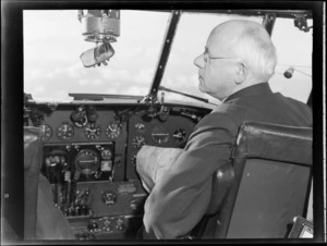 Portrait of the New Zealand Prime Minister Peter Fraser sitting at the controls of visiting British Vickers Viking passenger plane G-AJJN, [Wellington Airport?]