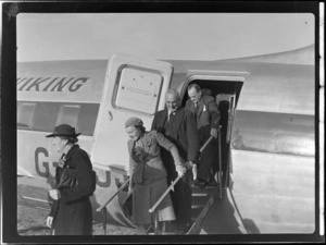 View of unidentified passengers disembarking from a demonstration flight on visiting British Vickers Viking passenger plane G-AJJN at Paraparaumu Airfield, Wellington Region