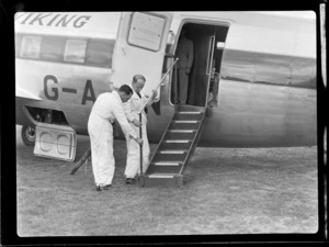 Unidentified plane crew adjusting gangway on visiting British Vickers Viking passenger plane G-AJJN demonstration flight at [Paraparaumu Airfield, Wellington Region?]