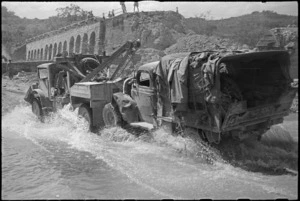 New Zealand breakdown truck towing vehicle over deviation alongside demolished bridge over Pisa River, Italy, World War II - Photograph taken by George Kaye