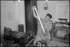 F D Morgan reading strip of film from sound recording machine used to locate enemy guns near Florence, Italy, World War II - Photograph taken by George Kaye