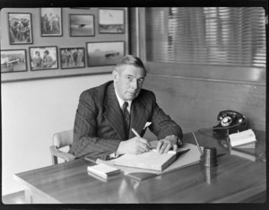 Portrait of Sir Leonard Monk Isitt, sitting at desk, writing in book