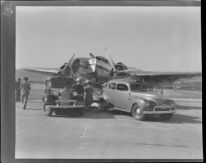 Two NZNAC (New Zealand National Airways Corporation) Dunedin Taxis in front of a Lockheed Lodestar ZK-AHX airplane 'Karoro', Taieri
