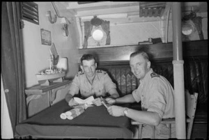Lieutenant Commander G T McCarthy and Sub Lieutenant R E Barritt read newly arrived mail on their naval motor launch at Bari, Italy - Photograph taken by George Bull